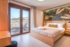 A bedroom with a large bed, a wooden headboard, a view through a sliding door, and a wall-mounted artwork. - Sia Elafonisi Pool House (Chrysoskalitissa, Kreta)