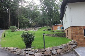 A residential property with a stone wall, a grassy lawn, and a building with a brick facade. - Holiday apartment with 2 bedrooms (Crinitzberg)