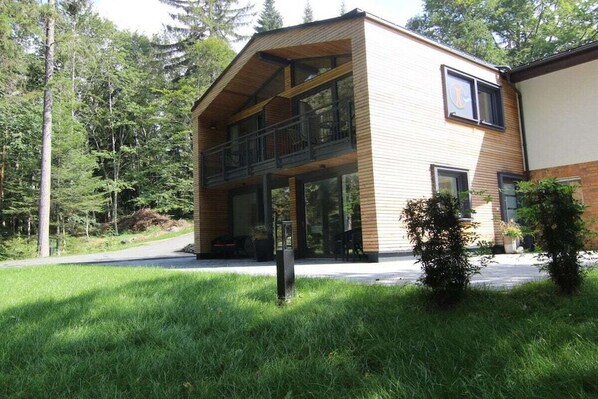 A two-story building with a balcony, surrounded by greenery and trees. - Holiday apartment with 2 bedrooms (Crinitzberg)