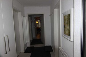 A hallway with a black carpet leading to a room with a radiator and a framed picture on the wall. - Holiday apartment with 2 bedrooms (Crinitzberg)