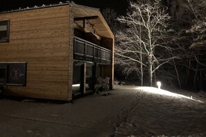 A wooden cabin with a balcony, surrounded by snow-covered ground and trees. - Holiday apartment with 2 bedrooms (Crinitzberg)