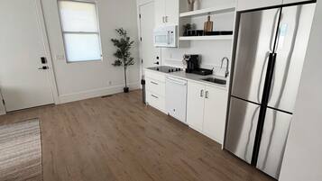 Een moderne keuken met witte kasten, een roestvrijstalen koelkast, een magnetron en een spoelbak.