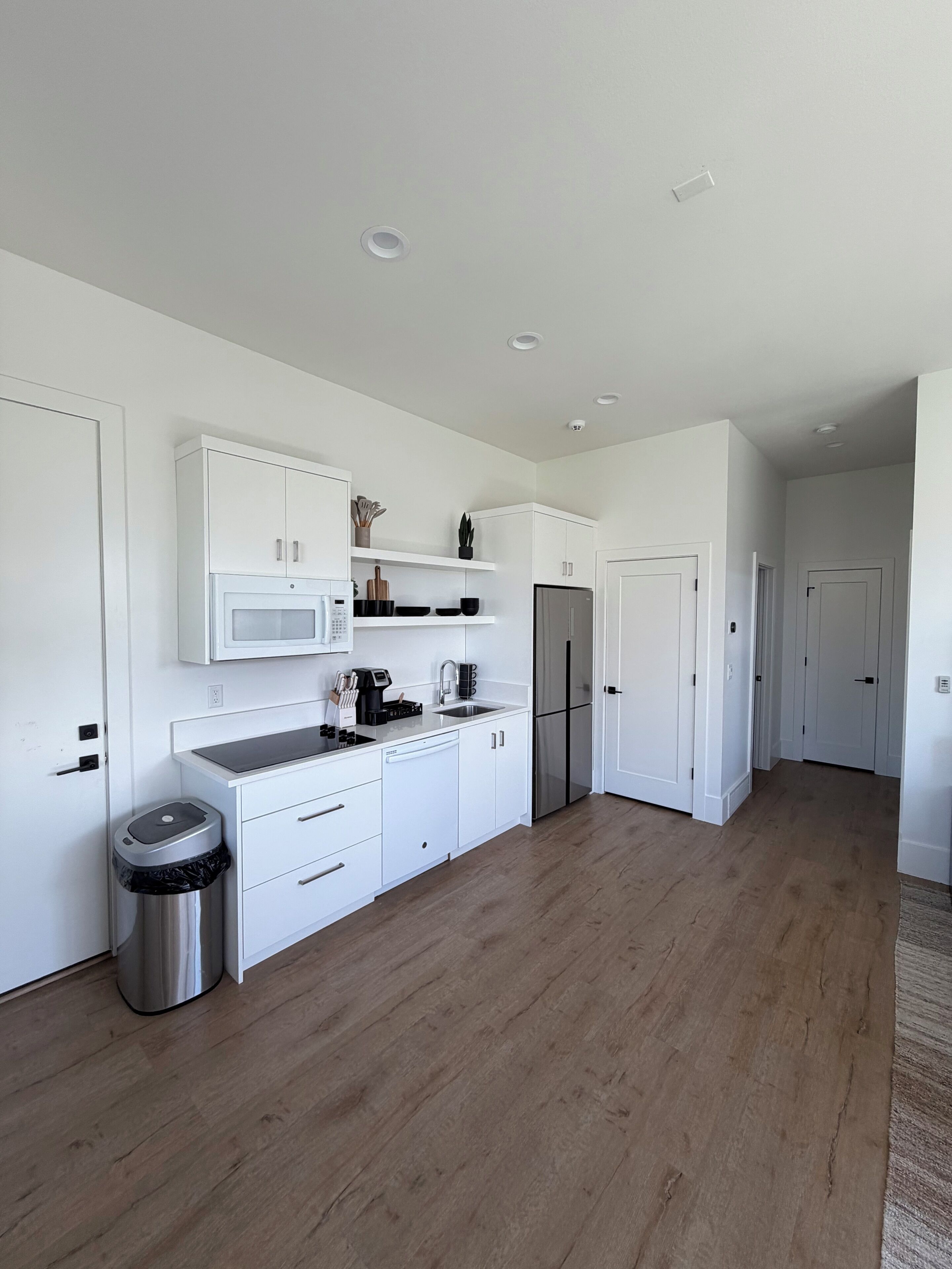 A modern kitchen with white cabinetry, a stainless steel refrigerator, and a built-in microwave.
