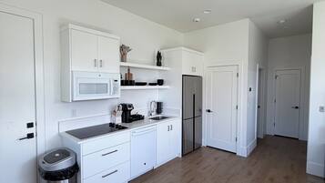 A modern kitchen with white cabinetry, a stainless steel refrigerator, and a built-in microwave.