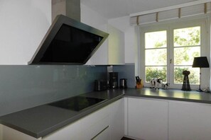 Une cuisine équipée d’une cuisinière intégrée, d’une machine à café et d’une fenêtre donnant sur un paysage verdoyant.