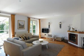 A spacious living room with a sofa, armchairs, a coffee table, and a fireplace. - Living at Dornenhaus 05 (Ostseebad Ahrenshoop)