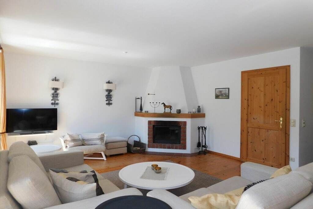 Un salon avec une cheminée, des canapés, un téléviseur et une porte en bois.