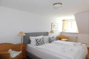 Ein Schlafzimmer mit einem Bett, zwei Nachttischen, einer Lampe, einem Fenster und einem Wandbild.