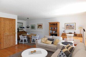 A living room with a sofa, a coffee table, and a dining area with chairs and a table. - Living at Dornenhaus 05 (Ostseebad Ahrenshoop)