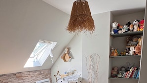 A child's room with a bunk bed, a hanging chair, a bookshelf, and a star-shaped decoration.