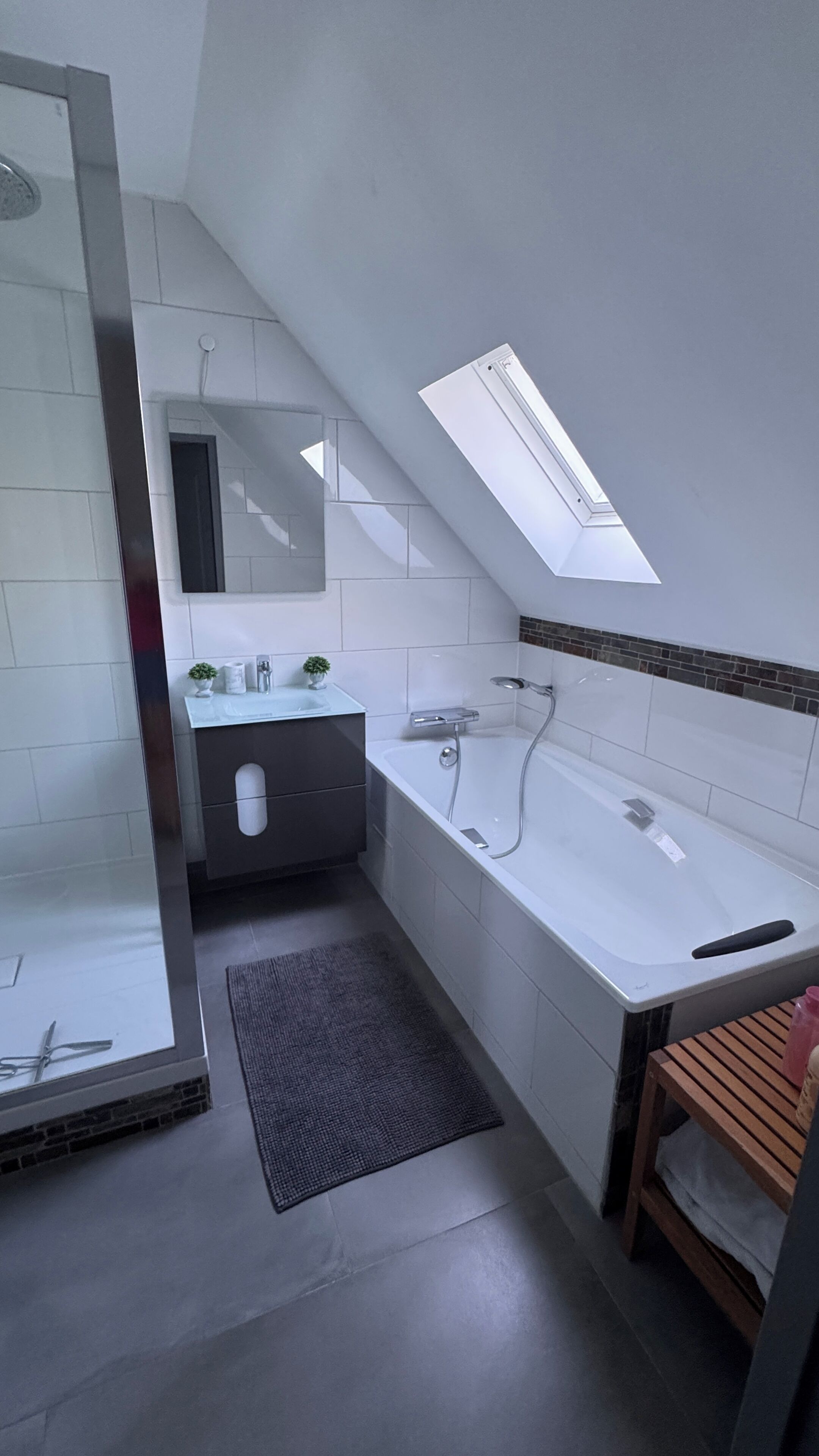 Une salle de bain moderne avec une douche à parois de verre, un lavabo blanc et une baignoire.