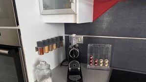 A kitchen with a coffee machine, spice rack, and a glass jar.