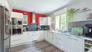 Une cuisine moderne avec des armoires blanches, des appareils en acier inoxydable et un mur d’accent rouge.