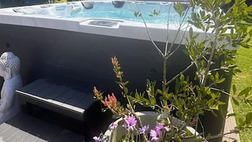 A hot tub with a wooden deck and a planter with flowers.