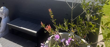 Un jacuzzi con terraza de madera y un macetero con flores.