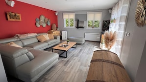 A modern living room with a grey sofa, a wooden coffee table, and a red accent wall.