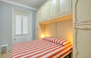 A bedroom with a bed, a small table, and a wardrobe with decorative moldings. - Gorgeous apartment in Camogli with WiFi (Camogli)