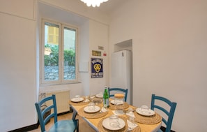 A dining area with a table set for four, a window with blinds, a refrigerator, and a poster on the wall. - Gorgeous apartment in Camogli with WiFi (Camogli)