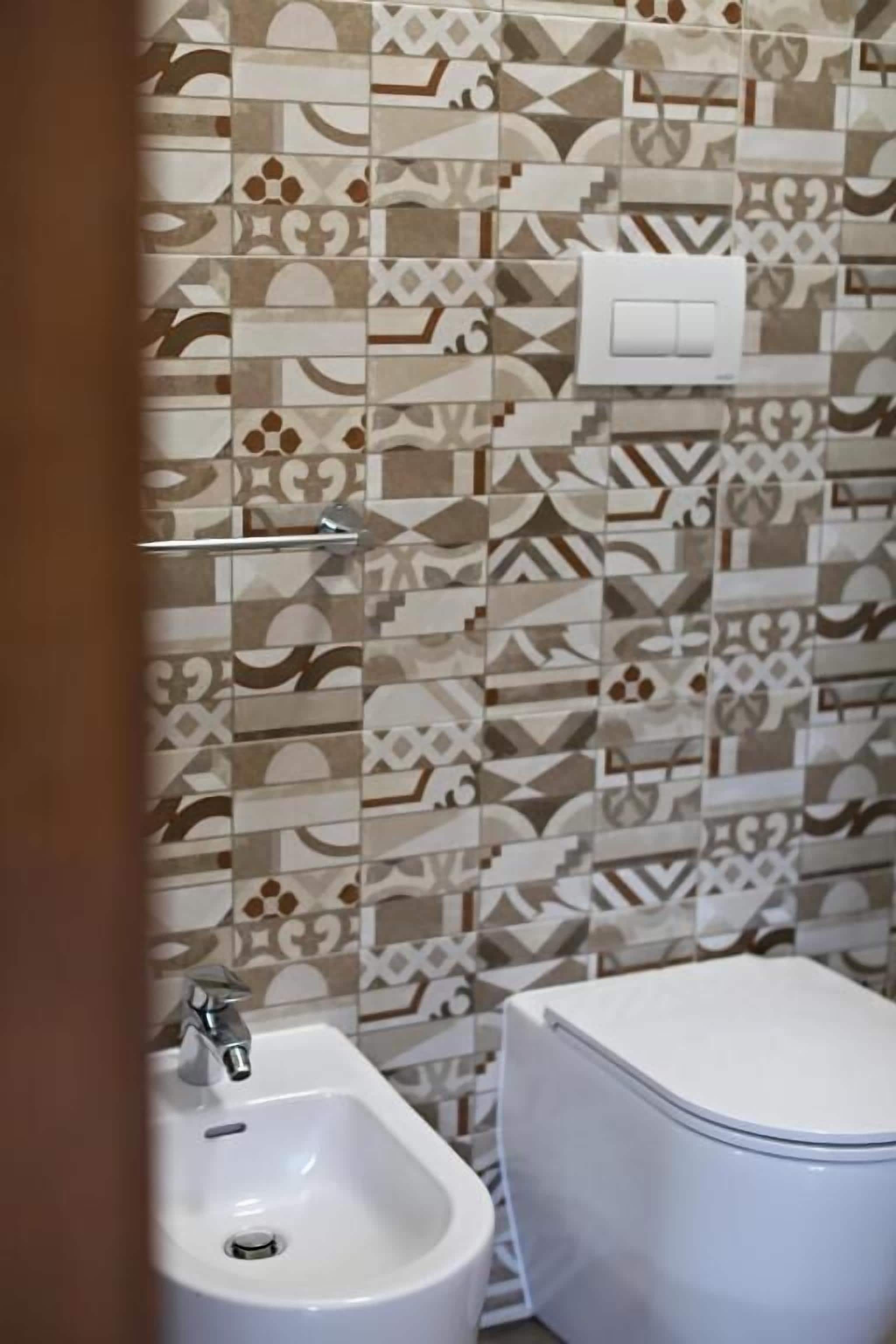 A bathroom with patterned tiles, a sink, and a toilet.