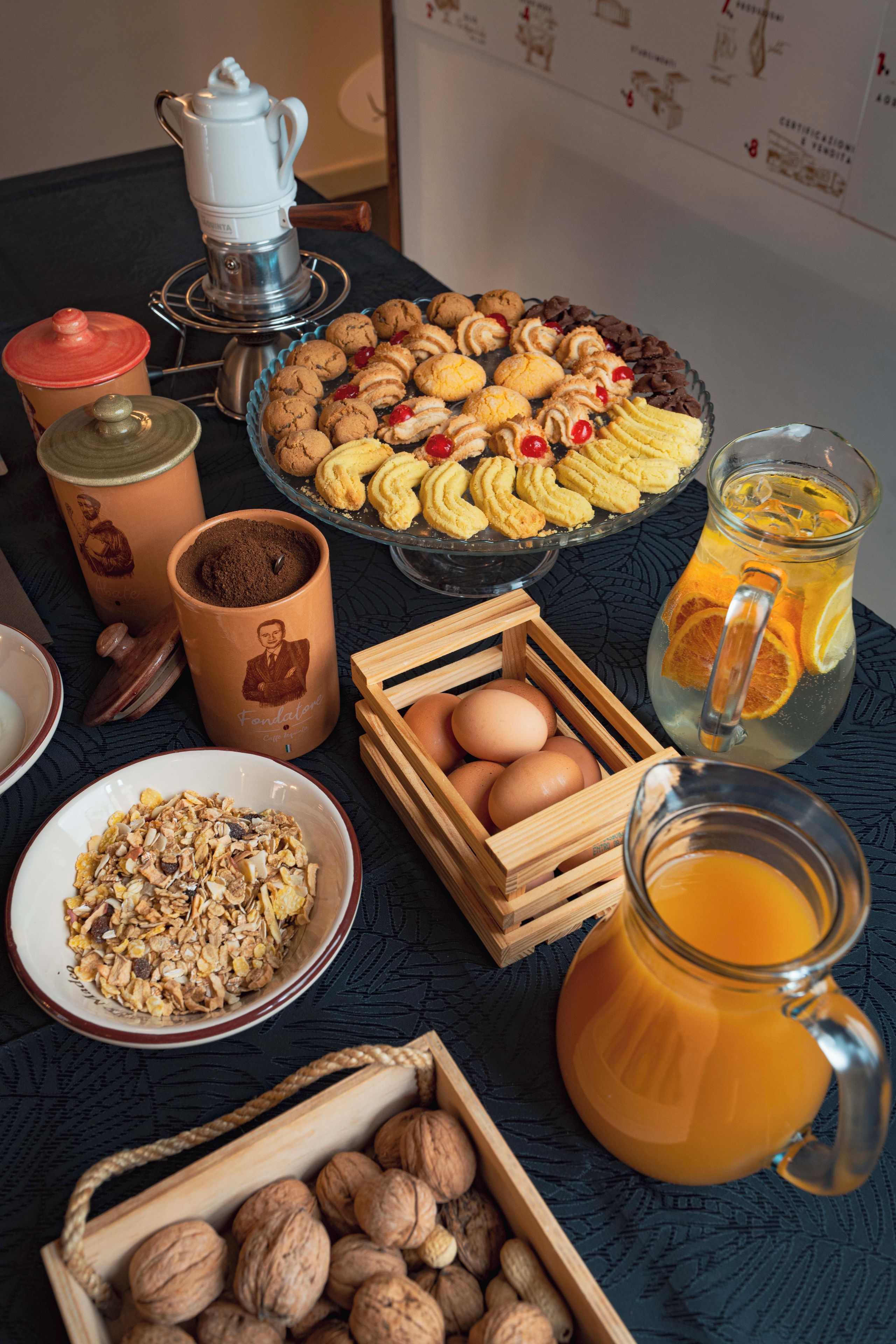 A breakfast table with various food items, including cookies, eggs, and a jug of orange juice.