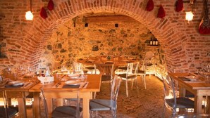 Un restaurante con un arco de piedra, mesas de madera y sillas transparentes.