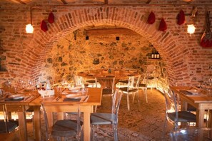 A restaurant with a stone archway, wooden tables, and clear chairs. - CASA MADEO B&B (Macchia Albanese / San Demetrio Corone)