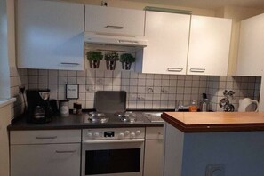 Eine Küche mit weißen Schränken, einem Herd, einem Backofen und einer Kaffeemaschine.