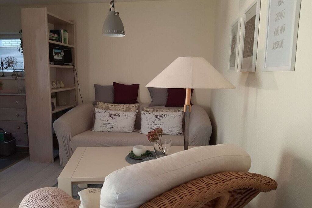 Ein Wohnzimmer mit einer Couch, einem Tisch, einer Lampe und einem Bücherregal.