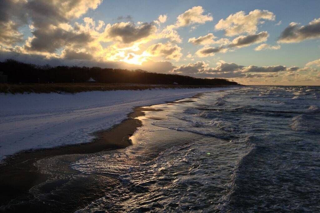 Ein Strand mit Wellen und einem Sonnenuntergang.