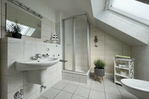 Un bagno moderno con doccia, lavabo e toilette, dotato di un lucernario e pareti piastrellate.