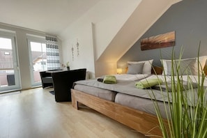 Ein Schlafzimmer mit Bett, Nachttisch und Blick ins Freie.