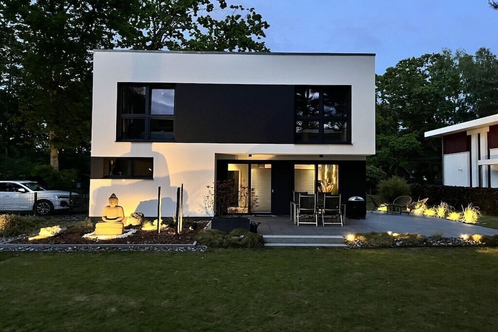 A modern two-story house with a flat roof, large windows, and a well-maintained lawn.