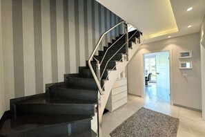 A modern interior with a black staircase, a white wall with vertical stripes, and a carpeted floor. - Seaside Lounge Rügen (Glowe)
