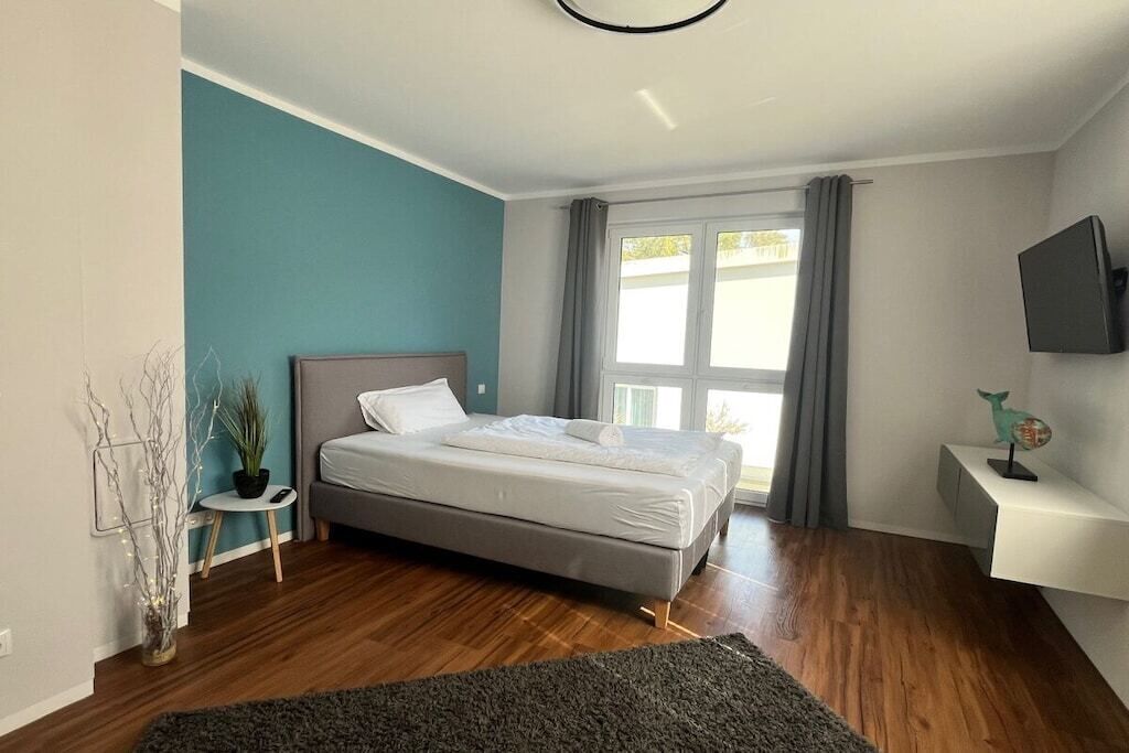 Une chambre à coucher avec un lit, une table de chevet, une télévision et une fenêtre avec des rideaux.