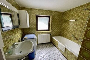 A bathroom with a sink, mirror, window, and bathtub. - Holiday apartment with 1 bedroom (Steffeln)