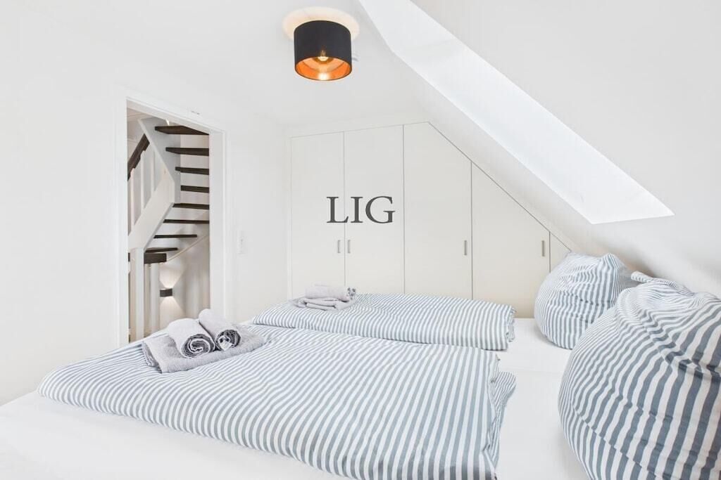 A bedroom with a sloped ceiling, a staircase, and a wardrobe with the word 'LIG' on it.
