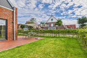 Ein Wohngrundstück mit Terrasse, Rasen und einem Haus im Hintergrund.