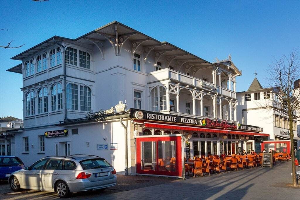 Un edificio con restaurante llamado 'Ristorante Pizzeria' en la planta baja, con mesas al aire libre.