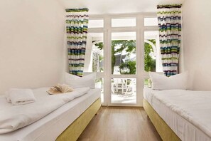 Habitación con dos camas, ventana con cortinas y vista al exterior.