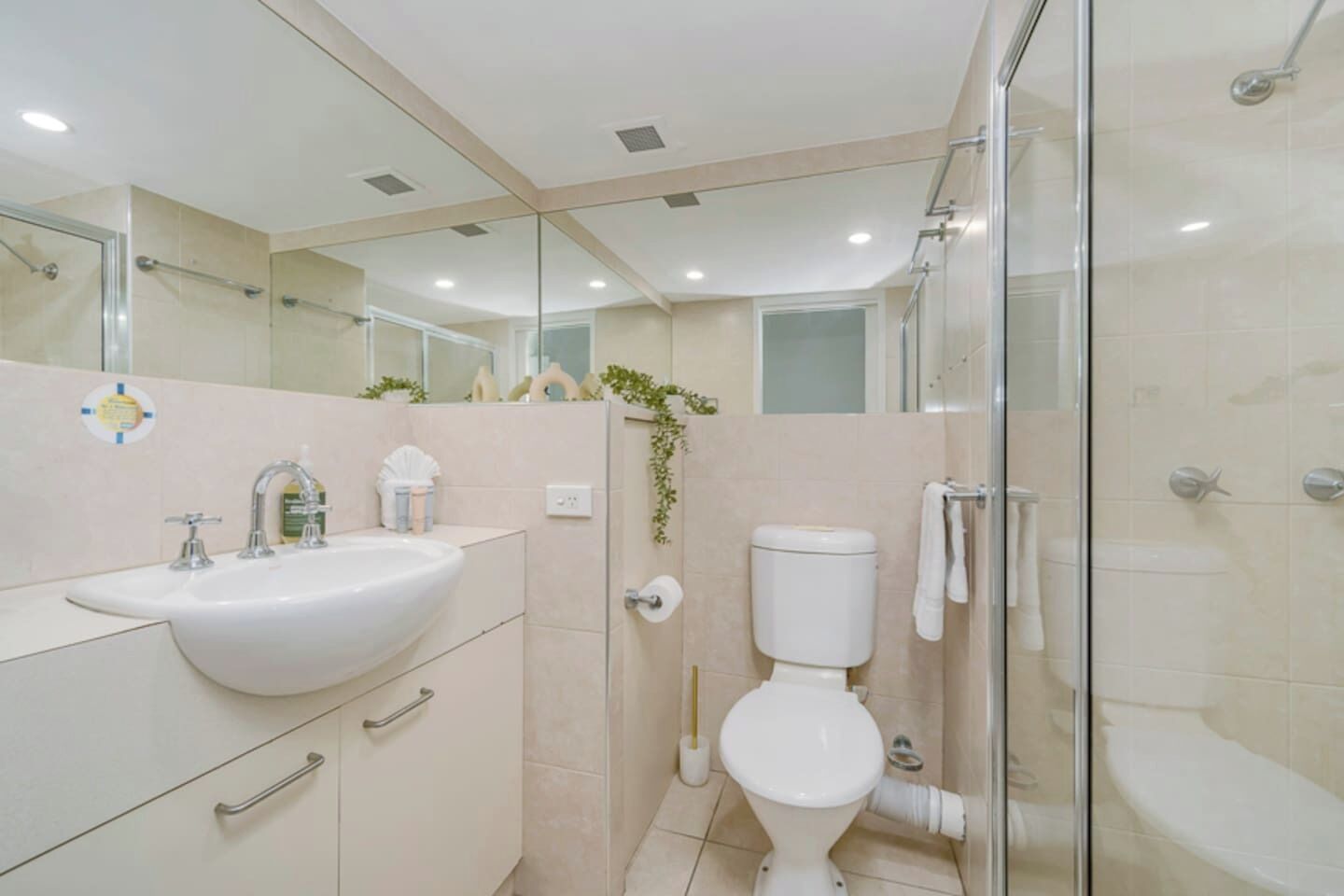 A modern bathroom with a glass shower enclosure, a white sink, and a toilet.