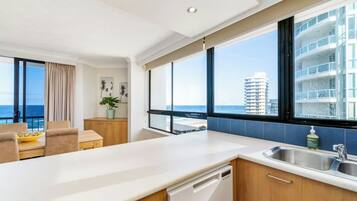 A modern kitchen with a view of the ocean and a dining area with a view of the city skyline.