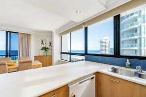 A modern kitchen with a view of the ocean and a dining area with a view of the city skyline. - Carrington Getaway - Ocean Views, Parking, Pool (Main Beach)