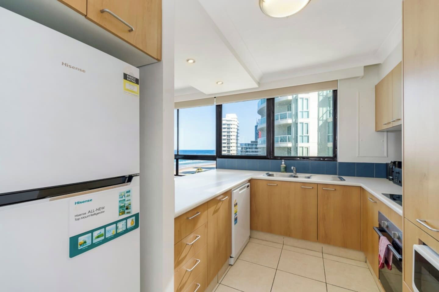 A modern kitchen with a view of the ocean, a Hisense refrigerator, and wooden cabinets.