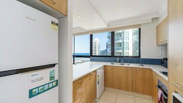 A modern kitchen with a view of the ocean, a Hisense refrigerator, and wooden cabinets.