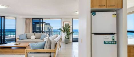 A modern living room with a sofa, a coffee table, and a view of the sea.
