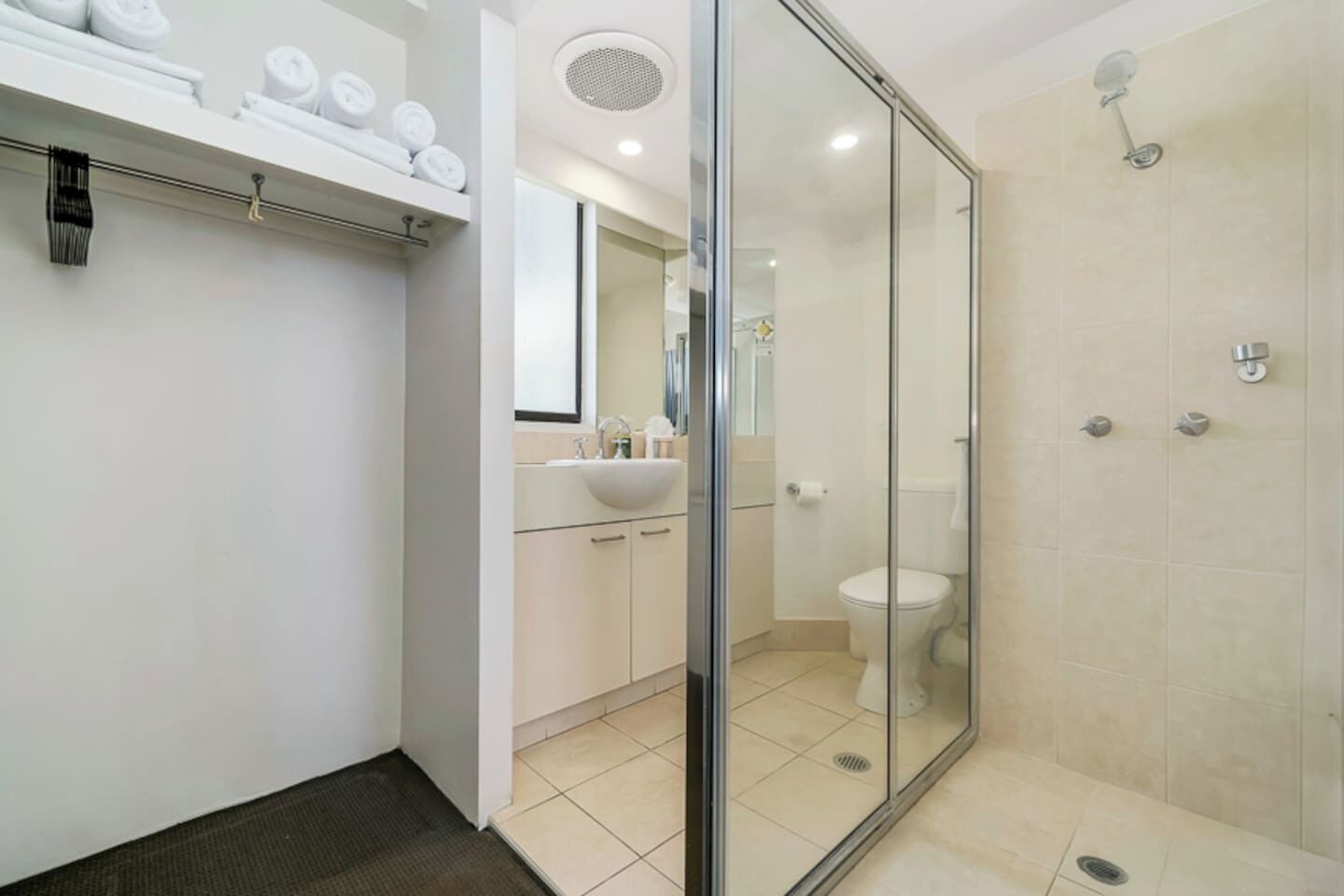 A modern bathroom with a glass shower enclosure, a toilet, and a sink area.