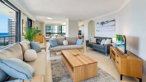 Uma sala de estar moderna com um conjunto de sofás, uma mesa de centro e uma televisão.