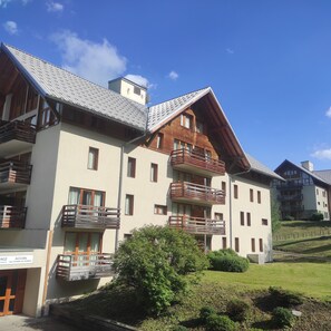 A multi-story hotel with balconies, a sign indicating 'ACCUEIL,' and a well-maintained lawn. - QUIET APARTMENT FOR 6 PEOPLE, 45 m², South-Facing Balcony, Pool, Sauna, Steam Room (Valloire)