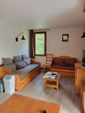 Ein gemütliches Wohnzimmer mit einer Couch, einem Holztisch und einem Fernseher.