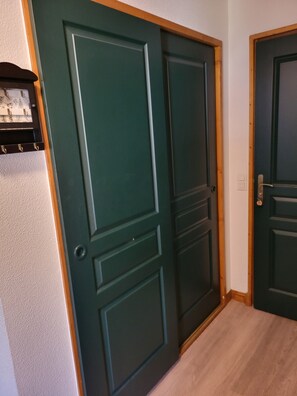 Eine geschlossene Tür mit Holzrahmen und einer weißen Wand mit einem Regal.